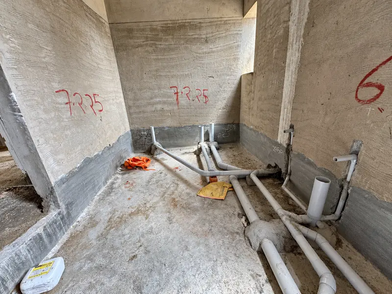 Wet-area wall junctions and drainage pipework before final finishes.
