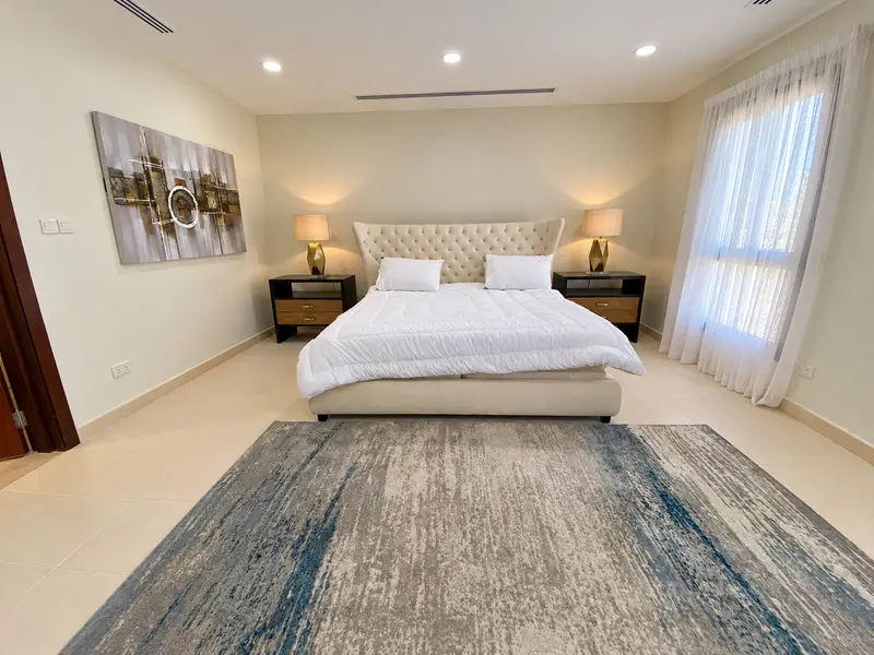 Bedroom layout with upholstered bed, accent lamps and a soft rug.