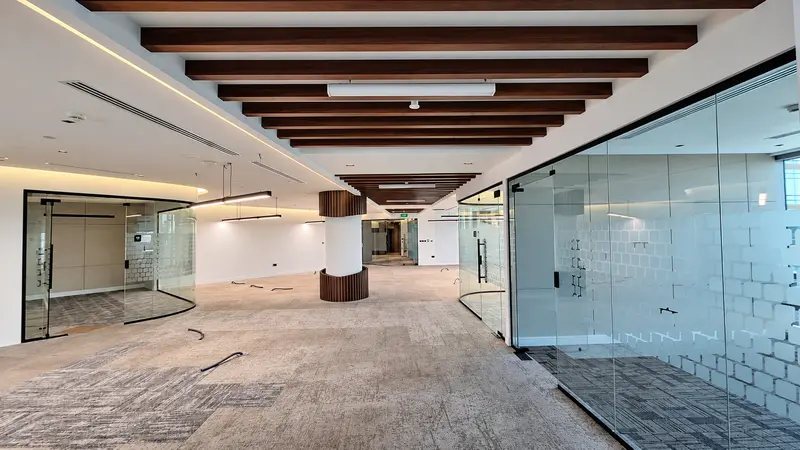 Office fit-out with ceiling baffles, glazing and carpet zones.
