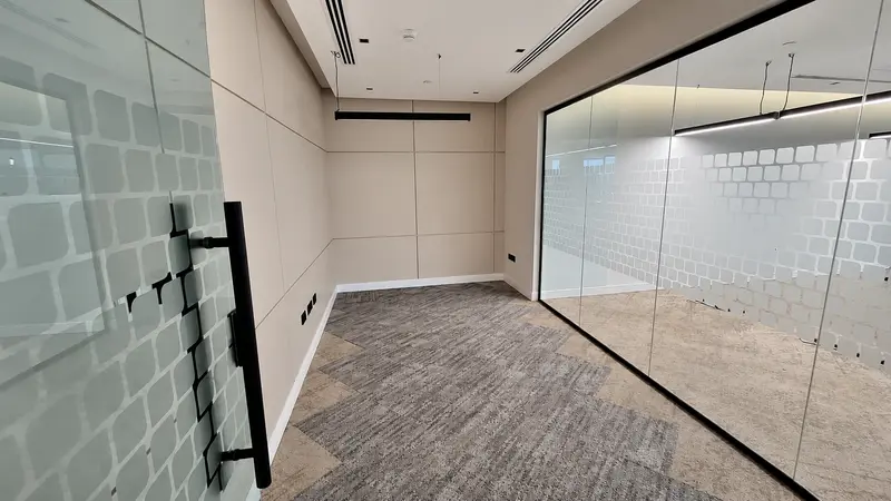 Office room with glazed partitions, acoustic finishes and integrated lighting.